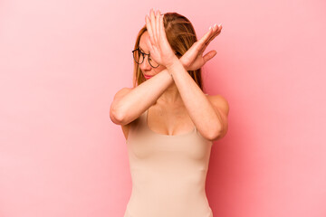 Obraz na płótnie Canvas Young caucasian woman isolated on pink background keeping two arms crossed, denial concept.