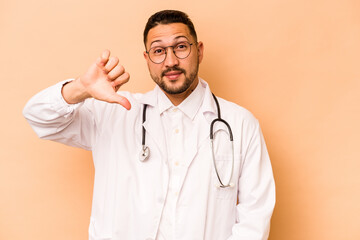 Hispanic doctor man isolated on beige background showing a dislike gesture, thumbs down....