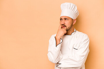 Hispanic chef man isolated on beige background relaxed thinking about something looking at a copy space.