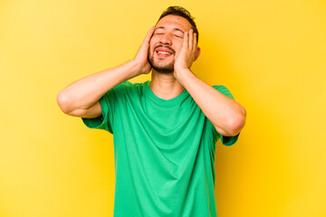 Fototapeta na wymiar Young hispanic man isolated on yellow background laughs joyfully keeping hands on head. Happiness concept.