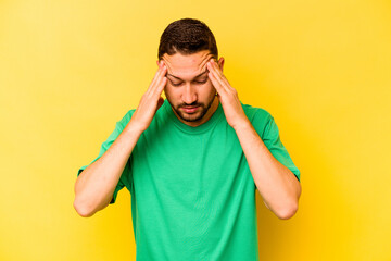 Young hispanic man isolated on yellow background touching temples and having headache.