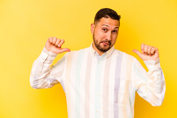 Young hispanic man isolated on yellow background feels proud and self confident, example to follow.