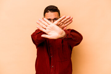 Young hispanic man isolated on beige background doing a denial gesture