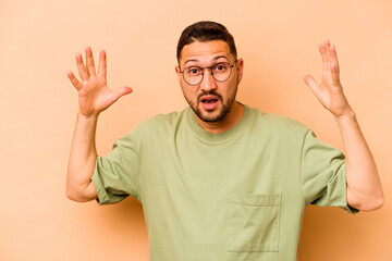 Young hispanic man isolated on beige background celebrating a victory or success, he is surprised...