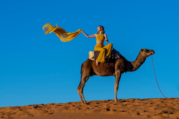 A Lovely Model Rides A Dromedary Camel Through The Saharan Desert On Their Camels In Morocco