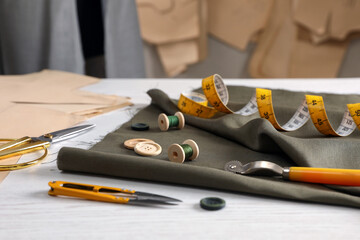 Set of sewing supplies and accessories with fabric on white wooden table indoors