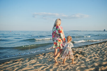 Mother and beautiful daughter having fun on the beach. Portrait of happy woman with cute little girl on vacation.