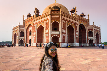 Young woman holding man hand while leading him to the Humayun Tomb monument in New Delhi
