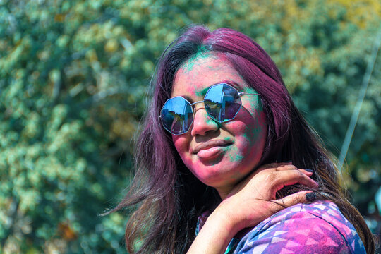 Portrait of happy young Indian girl with face covered with colors in Holi festival.