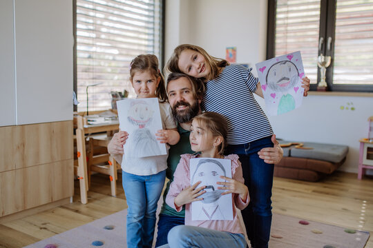 Father of three little daughters getting drawings from them at home.