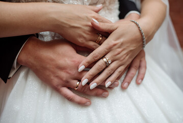 Bride and groom holding hands together on wedding day. Close up