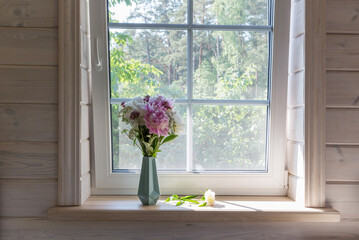 A bouquet of peonies on the windowsill