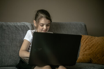 Dziecko bawiące się laptopem na kanapie - obrazy, fototapety, plakaty