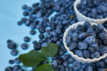Flat lay of fresh organic juicy blueberries in a bowl on blue background