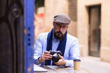 Photographer sitting in cafe outside checking the photos he took during his day