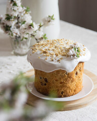 Traditional easter cake or sweet bread, apple brahces in bloom on white plate on light linen tablecloth. Side view, selective focus. Easter treat, holiday symbol