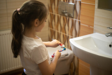 Dziewczynka nakładająca pastę do zębów na szczoteczkę - obrazy, fototapety, plakaty