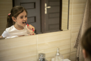 Dziewczynka myjąca swoje zęby przed lustrem