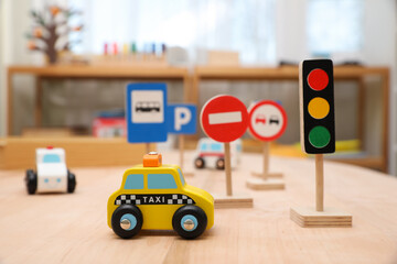 Different miniature road signs and cars on wooden table. Montessori toy - obrazy, fototapety, plakaty