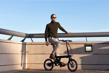 Obraz premium Young man riding an electric bike as a sustainable urban transportation to avoid pollution in the city.