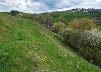 Fototapeta na wymiar Spring rural hills landscape with terrace fields, farm flowering trees, hilly meadows. Sutkivtsi village, Khmelnytsky region, Ukraine.