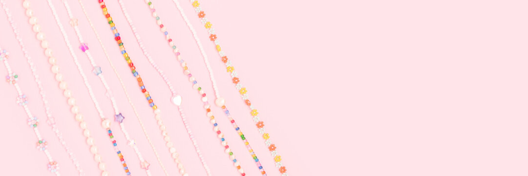 Banner with necklaces made from colorful beads and pearls on a pink background with place for text.