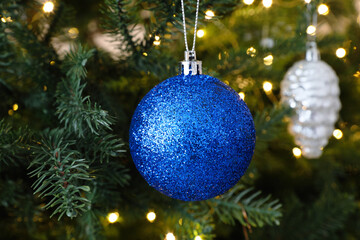 Fototapeta na wymiar Beautiful blue Christmas ball hanging on fir tree branch, closeup