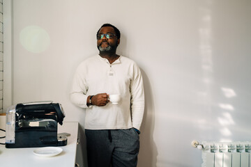 Black man wearing eyeglasses drinking coffee while having breakfast