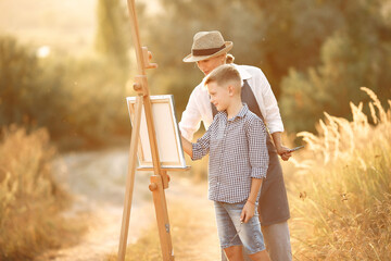 Mother with son painting in a field - Powered by Adobe