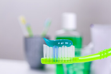 Toothbrush with paste near mouthwash on blurred background, closeup