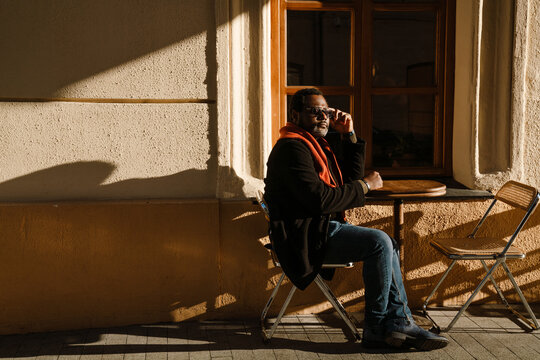 Black Man Wearing Sunglasses Sitting In Street Cafe Outdoors