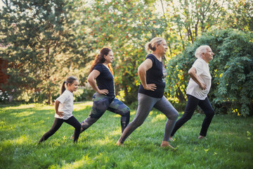 Four females of different generations of family doing physical exercises for stretching legs...