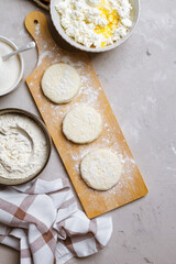 Raw cottage cheese pancakes on a wooden board. Healthy and delicious breakfast or lunch. Top view 