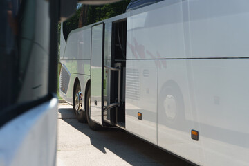 Naklejka premium Modern buses for transporting people stand at the bus stop. Close-up of an open bus door. Light back.