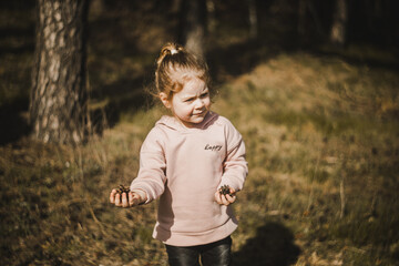 Małe dziecko trzymające w dłoni szyszki z lasu