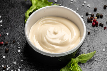 Bowl with tasty white sauce on dark background. Food recipe background. Close up