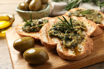 Tasty bruschettas with pesto and rosemary on wooden board, closeup