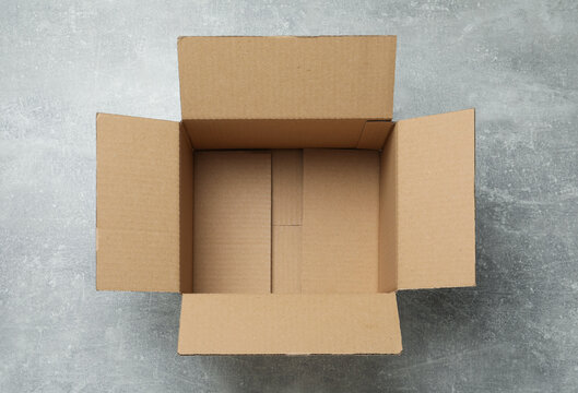 Empty open cardboard box on grey table, top view