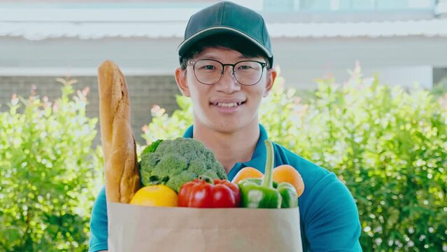 Food Delivery concept. Asian delivery man hand giving bag of food, fruit, vegetable delivery to costomer grocery delivery service.