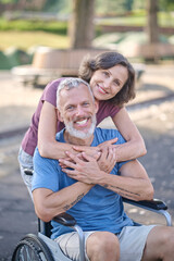 A woman and a man in a wheel chair feeling happy and smiling