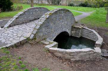 arch bridge, stone granite with railings to the arch. english landscape park. the grassy ditch of...