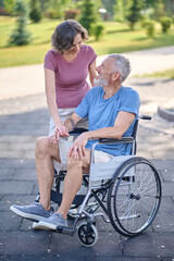 Obraz premium A man in a wheel chair and his wife on a walk in the park