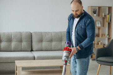 Man doing house work with accumulator vacuum cleaner