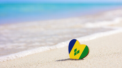 Flag of Saint Vincent and the Grenadines in the shape of a heart on a sandy beach. The concept of the best vacation in Saint Vincent and the Grenadines resorts