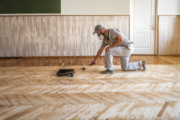 worker lacquering parquet floors