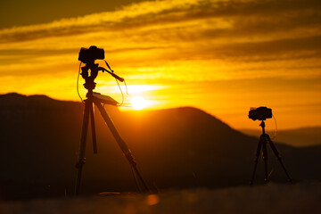 Camera on tripod take photo from sunrise over mountain