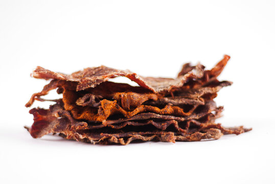 Slices of Beef Jerky Stacked on a White Background.