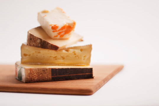 Four Assorted French Cheeses Stacked on a Board.