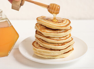 honey pouring on a stack of pancakes. traditional fluffy pancakes. comforting food