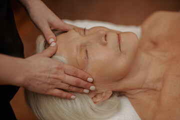 Fototapeta na wymiar A senior woman having a face massage in a beauty salon